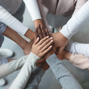 Close up of international business team showing unity with putting their hands together on top of each other. Concept of teamwork, top view